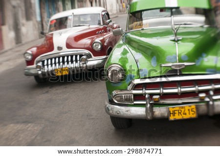 HAVANA, CUBA - JUNE, 2011: Tilt shift view of brightly colored vintage American taxi cars share the road in Central Havana.