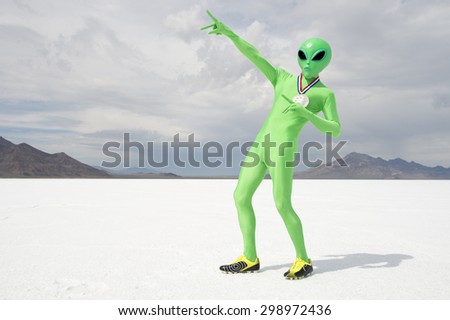Green alien track star athlete wearing gold medal celebrating with lightning bolt pose on stark white planet background