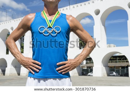 RIO DE JANEIRO, BRAZIL - MARCH 6, 2015: Illustrative editorial man with Olympic rings gold medal stands outdoors in the plaza in front of the famous Lapa Arches landmark.