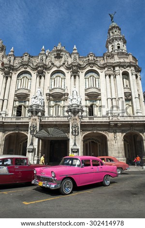 HAVANA, CUBA - JUNE, 2011: Bright pink vintage American car stands parked in front of the landmark architecture of the Great Theater of Havana.