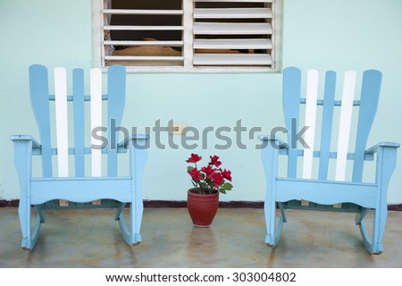 Traditional wooden rocking chairs in front of blue walls on the porch of a rural Cuban house in Vinales, Cuba