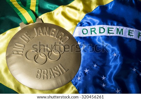 RIO DE JANEIRO, BRAZIL - FEBRUARY 3, 2015: Illustrative editorial of large gold medal commemorating the 2016 Olympic Games sits on Brazil flag background.