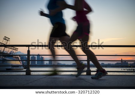 Motion blur silhouettes of joggers running at sunset on the Hudson River boardwalk in New York City