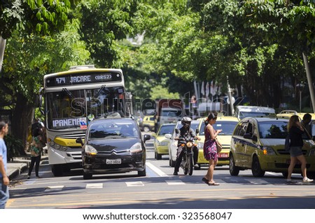 RIO DE JANEIRO, BRAZIL - MARCH 15, 2013: Traffic stopped at a shady intersection in the leafy neighborhood of Ipanema features city bus, taxis, motorcycles and pedestrians.