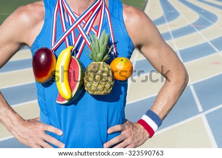 Winner of healthy eating competition standing at running track with fruit medals including orange, watermelon, banana, mango, and pineapple