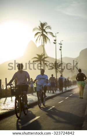 RIO DE JANEIRO, BRAZIL - FEBRUARY 11, 2014: Cyclists and joggers share the bike path alongside pedestrians on the boardwalk in a typical sunset scene on Ipanema Beach.