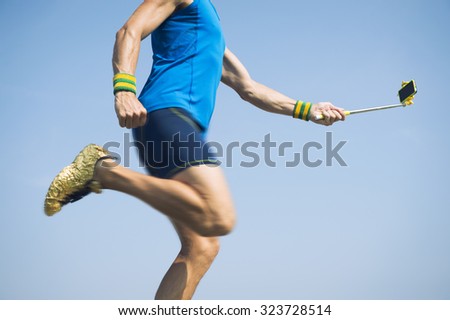 Modern athlete in gold shoes running with his smartphone on the end of a selfie stick