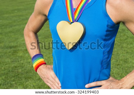 Gay athlete standing with heart gold medal and rainbow ribbons in front of a green playing field