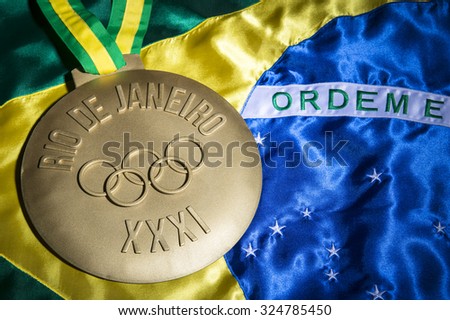 RIO DE JANEIRO, BRAZIL - FEBRUARY 3, 2015: Large gold medal commemorating the XXXI 31st Olympic Games in 2016 sits on Brazil flag background.