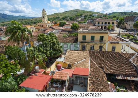 White clouds float in blue sky above the terra cotta rooftops of the historic colonial architecture in the UNESCO heritage center of Trinidad, Cuba