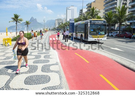 RIO DE JANEIRO, BRAZIL - APRIL 1, 2014: A city bus stops beside the boardwalk bike path on Avenida Vieira Souto in Ipanema, painted red for safety.