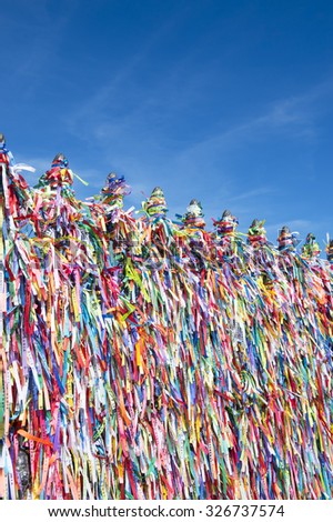 Colorful religious Brazilian wish ribbons tied on gate at the Church of Nosso Senhor do Bonfim in Salvador Brazil under bright blue sky