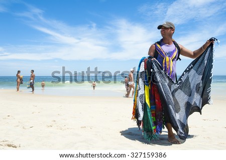 RIO DE JANEIRO, BRAZIL - MARCH 15, 2015: A beach vendor selling brightly colored sarongs carries his merchandise along Ipanema Beach.
