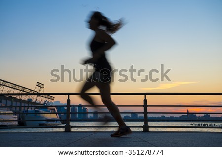 Silhouette of jogger running at sunset in front of the city skyline on the West Side in New York City