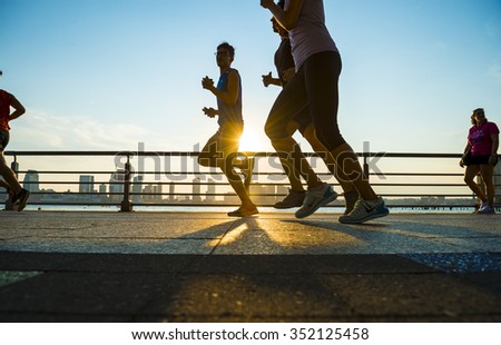 NEW YORK CITY, USA - AUGUST 15, 2015: Silhouettes of men run at sunset on the Hudson River boardwalk.