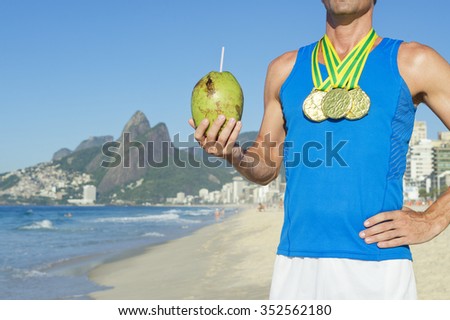 Man wearing gold medals celebrating with coconut on Ipanema Beach in Rio de Janeiro Brazil