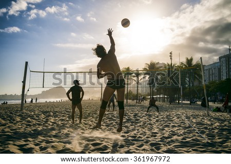 RIO DE JANEIRO, BRAZIL - OCTOBER 30, 2015: A group of young Brazilian men play a game of volleyball at sunset at the Leme end of Copacabana Beach.