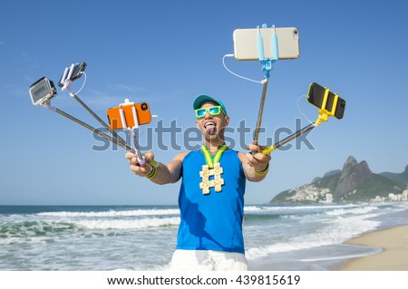Hashtag gold medal athlete posing for a picture with mobile phones on selfie sticks on Ipanema Beach in Rio de Janeiro, Brazil