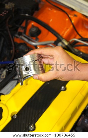 technician hand holding a piston with engine room background