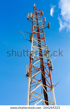 High red and white antenna mast on blue sky background
