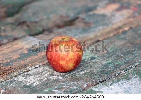 Red apple on the painted peeling green paint plank table