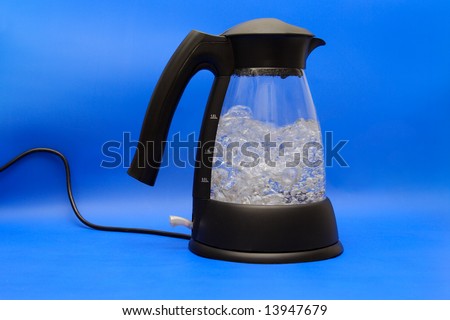 Water boiling in the glass electric kettle on blue background