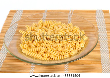 Macaroni in a transparent plate on straw mat isolated on white background
