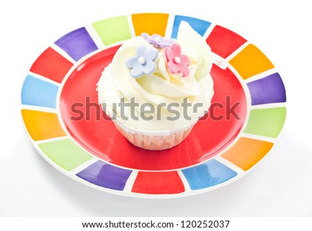 red and blue flower decorated cupcake on colorful plate isolated