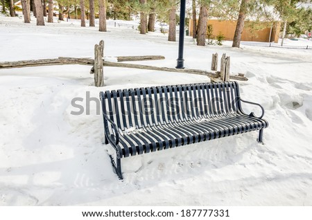 Empty Metal Bench in a Park Covered in Snow