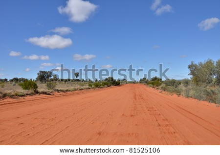A Red Unsealed Road In The Australian Outback and a Clear Blue Sky