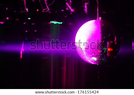 Purple shining disco ball and party lights at night club