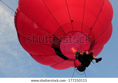 Photo of a man in red hot air balloon taken from the bottom angle