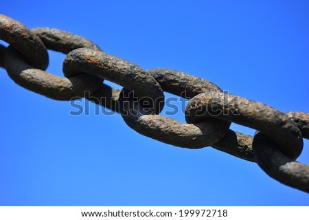 Links of a rusty old chain against blue sky