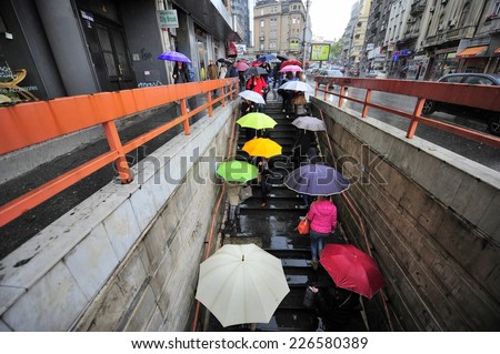 SERBIA, BELGRADE - APRIL 30, 2014: People with umbrellas struggle heavy rain in april in Belgrade. Heavy rains in april and may in Serbia caused terrible floods in region