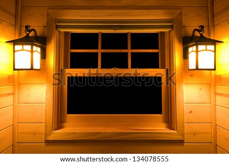 Inside view of a cedar cabin window with lights on