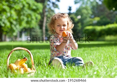 Child (girl) eats fruit on a grass