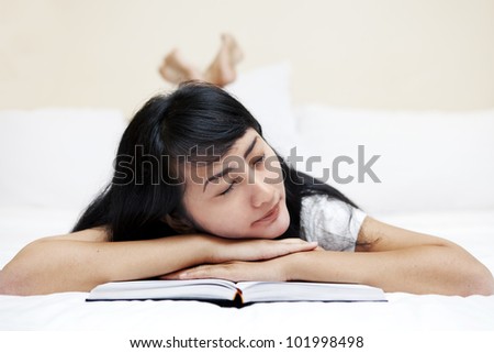 Asian woman falls to sleep with a book on bed. Shot in studio