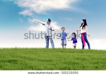Asian family of father, mother, and two kids  having a quality time in meadow. Shot at summer