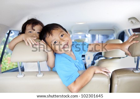 Asian children ready for a road trip posing in car