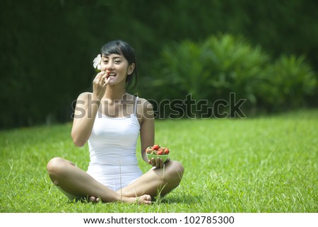 Healthy lifestyle photo concept with woman eating strawberry outdoor