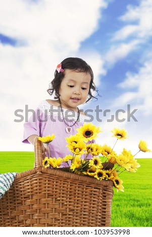 Sweet little girl in a meadow with sunflowers on the basket