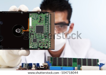 A scientist showing a computer hard disk shot in studio against blue background