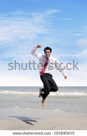 Young businessman jumping at the beach to celebrate his success