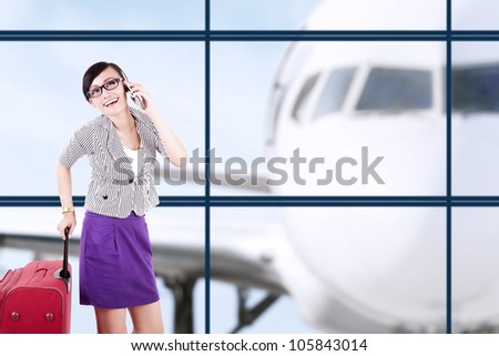 Businesswoman with big suitcase having a conversation on the phone, shot at airport