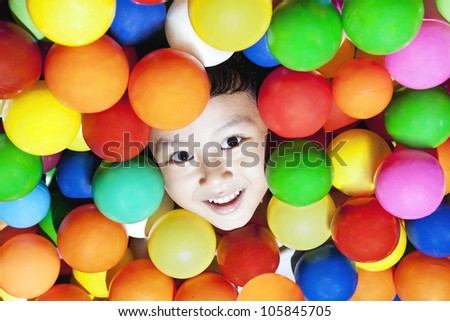 Happy asian boy playing with colorful balls, shot at playground