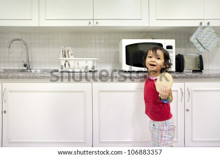 Cute little girl holding a bread in kitchen. shot in the kitchen with modern interior