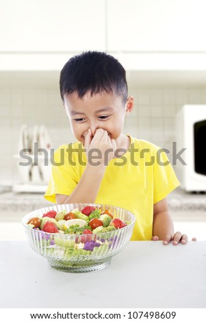 That smells bad! Young asian child covering his nose from vegetables. shot in kitchen