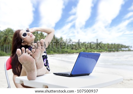 Young asian businesswoman with laptop enjoying beautiful beach. shot outdoor