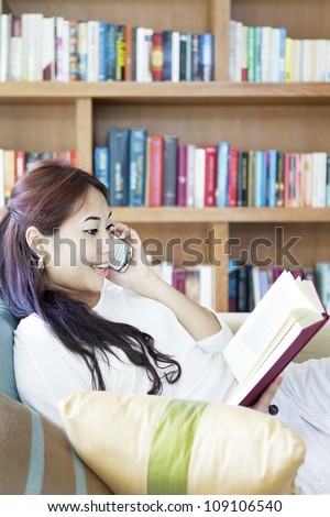 Portrait of asian woman enjoying leisure time by reading book and talking on the phone
