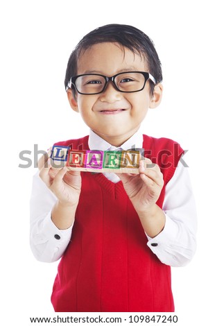 Portrait of asian elementary school student showing letter blocks spelling out LEARN. shot in studio isolated on white